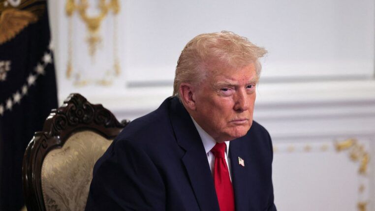 Homem branco com idade elevada de terno e gravata vermelha