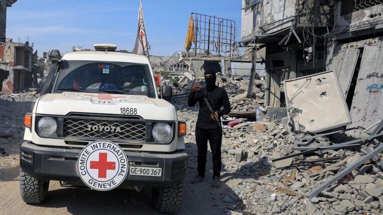 Carro da Cruz Vermelha é acompanhada por guarda do Hamas em meio aos escombros