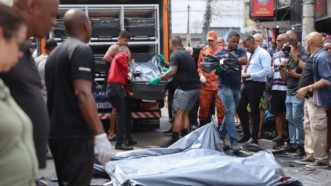 Homens carregam corpos de vítimas em deslocamento para um caminhão