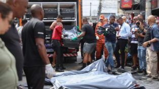 Homens carregam corpos de vítimas em deslocamento para um caminhão