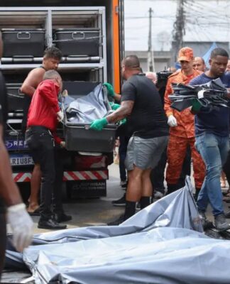 Homens carregam corpos de vítimas em deslocamento para um caminhão