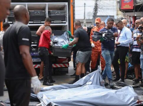 Homens carregam corpos de vítimas em deslocamento para um caminhão
