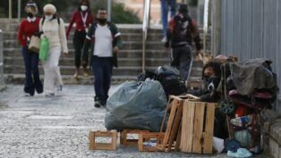Mulher em situação de rua limpa a entrada de sua barraca
