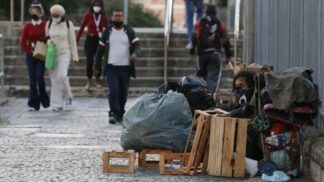 Mulher em situação de rua limpa a entrada de sua barraca