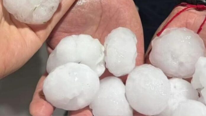 Imagem mostra pedras grandes de granizo em duas mãos