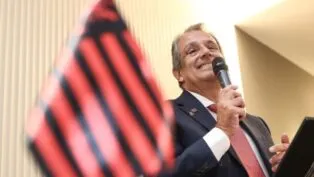 Bap discursa ao lado da bandeira do Flamengo