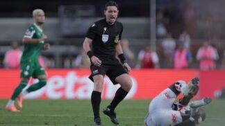 Árbitro Ramon Abetti Abel de pé, ao lado de um jogador do São Paulo no chão, durante partida contra o Palmeiras