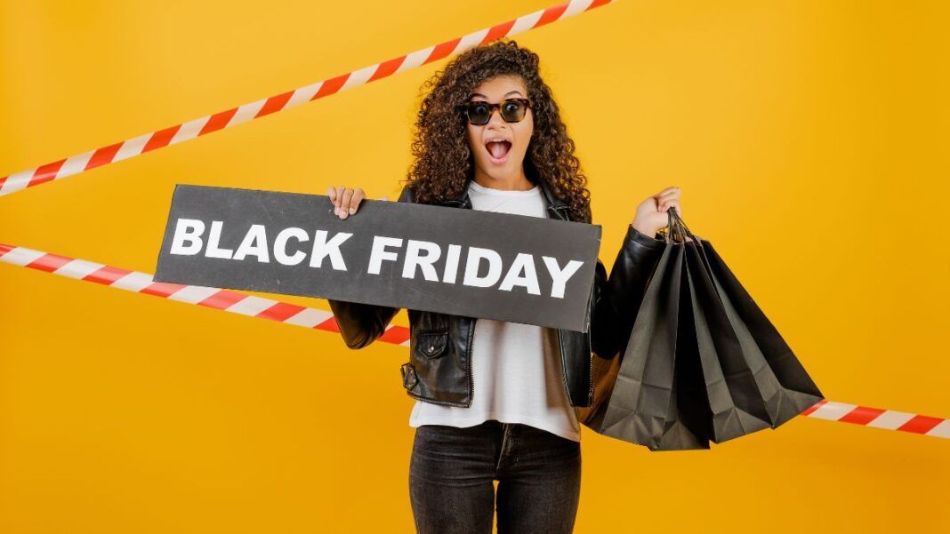 Mulher em fundo amarelo, segurando sacolas pretas e placa escrita black friday