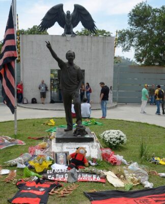 Entrada do CT Ninho do Urubu com faixas, flores e bandeiras do Flamengo em homenagem aos mortos