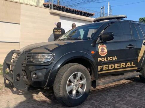 Carro da Polícia Federal está estacionado em frente a uma casa