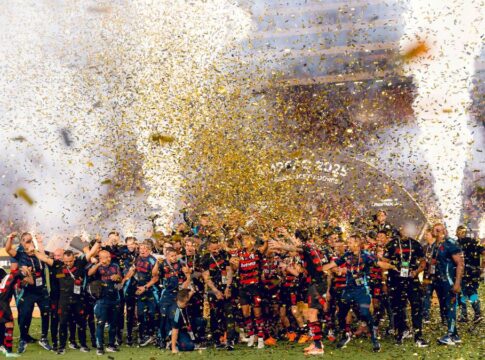 Jogadores do Flamengo festejam o tetracampeonato da Libertadores em meio a chuva de papel picado no gramado.