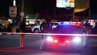 Policiais estão ao lado de um carro policial no local do crime, na cidade californiana