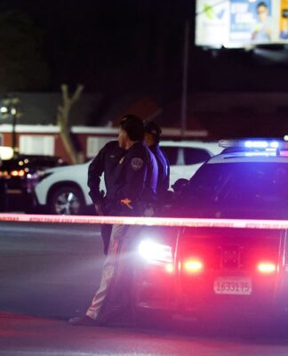 Policiais estão ao lado de um carro policial no local do crime, na cidade californiana