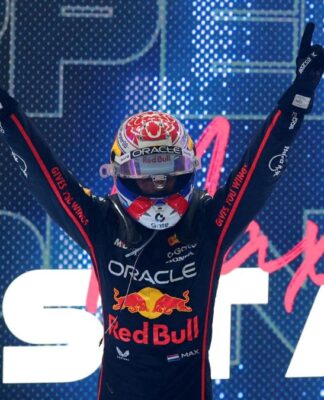 Max Verstappen, de capacete, comemora vitória à frente de telão com o seu nome