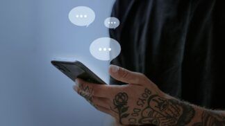 Homem segurando smartphone; balões transparentes contendo três pontinhos saem da tela