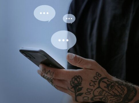 Homem segurando smartphone; balões transparentes contendo três pontinhos saem da tela