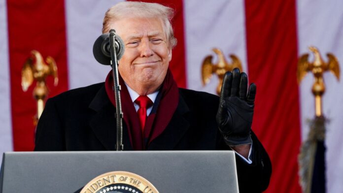 Donald Trump sorri diante de microfone com a bandeira dos EUA ao fundo