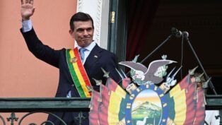 Rodrigo Paz com faixa presidencial na sacada, acenando para população boliviana