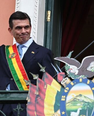 Rodrigo Paz com faixa presidencial na sacada, acenando para população boliviana