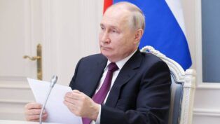 O presidente Vladimir Putin segura uma folha de papel diante do microfone