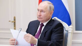 O presidente Vladimir Putin segura uma folha de papel diante do microfone