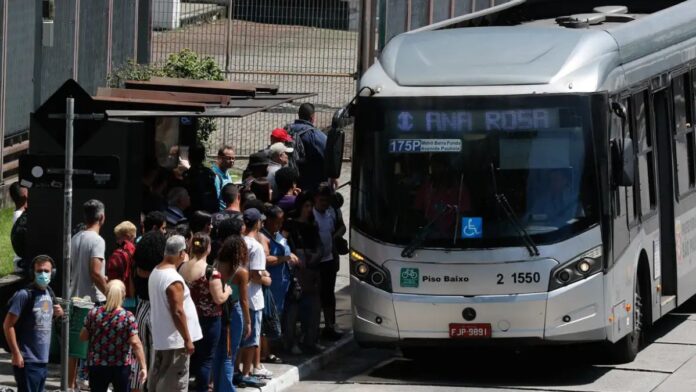 Fila de pessoas à espera do ônibus, ao lado