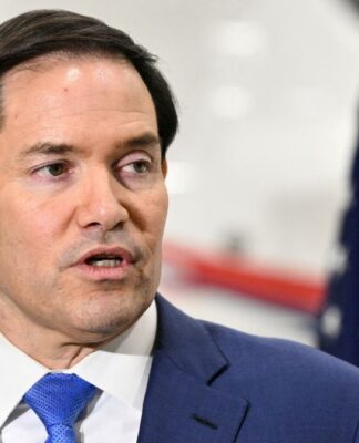 Marco Rubio fala aos repórteres com bandeira dos EUA ao fundo