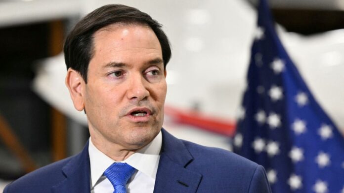 Marco Rubio fala aos repórteres com bandeira dos EUA ao fundo