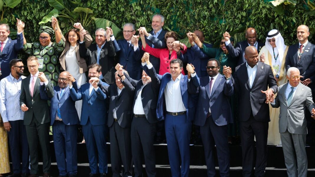 Delegados de vários países, com as mãos dadas e erguidas, posando para foto oficial da COP30