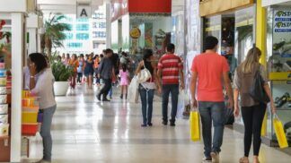 Pessoas circulando e portando sacolas de compras num shopping center