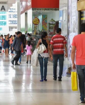 Pessoas circulando e portando sacolas de compras num shopping center