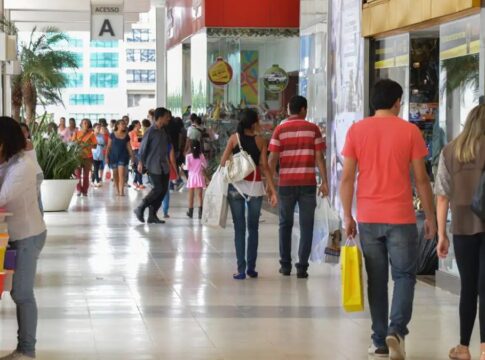 Pessoas circulando e portando sacolas de compras num shopping center