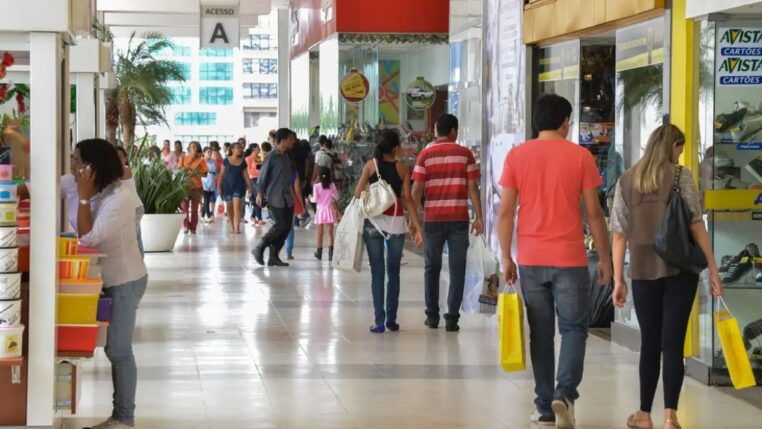 Pessoas circulando e portando sacolas de compras num shopping center