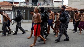 Policiais conduzem suspeitos algemados por uma rua do Rio