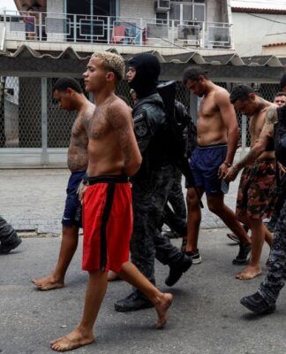 Policiais conduzem suspeitos algemados por uma rua do Rio