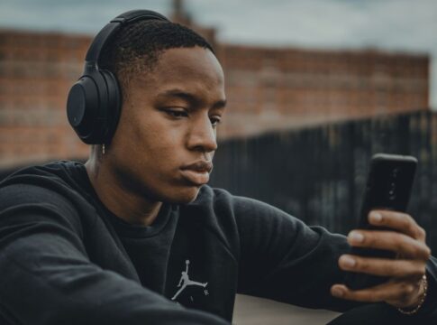 Homem ouvindo música no fone de ouvido e olhando o celular