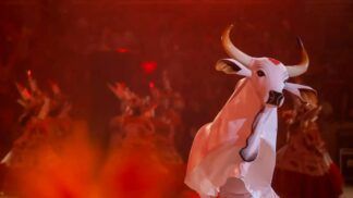 Boi-bumbá de cor branco com fundo vermelho durante manifestação cultural