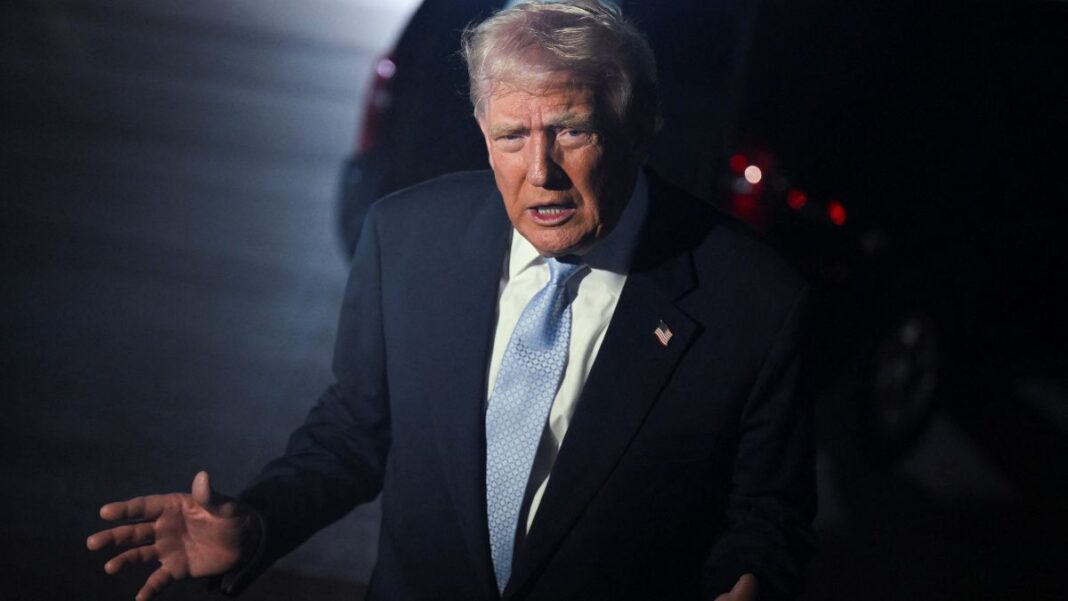 Trump gesticula após desembarcar de avião, à noite.