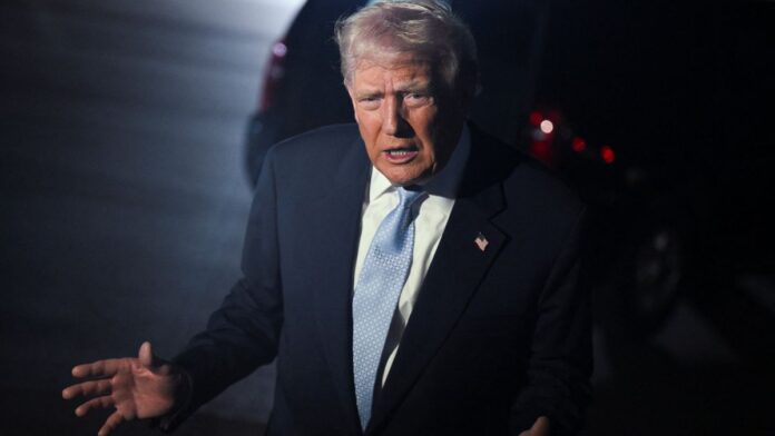 Trump gesticula após desembarcar de avião, à noite.