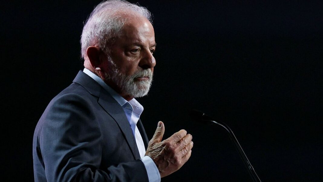 Lula faz gesto com a mão direita enquanto faz declaração ao microfone