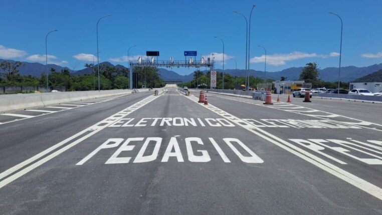 Mensagem "eletrônico pedágio" escrito no asfalto antes de um pórtico de cobrança