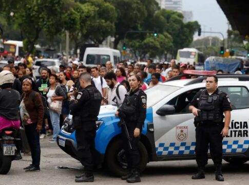 Policiais armados à frente de carros da própria polícia.