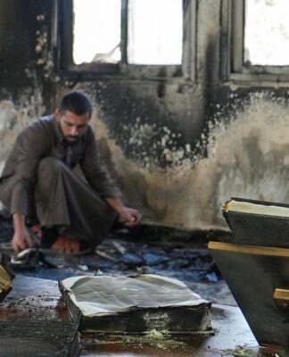 Homem dentro de uma mesquita com as paredes danificadas por chamas