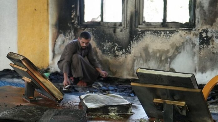 Homem dentro de uma mesquita com as paredes danificadas por chamas