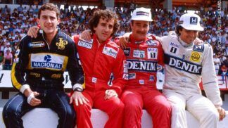 Ayrton Senna, Alain Prost, Nigel Mansell e Nelson Piquet estão sentados numa mureta com seus macacões durante um GP