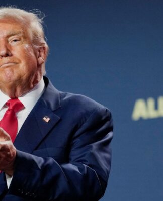 Trump aplaude com expressão de ironia à frente de um fundo azul