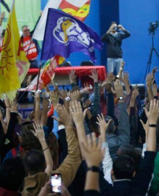 Multidão de sindicalizados em greve levantando as mãos