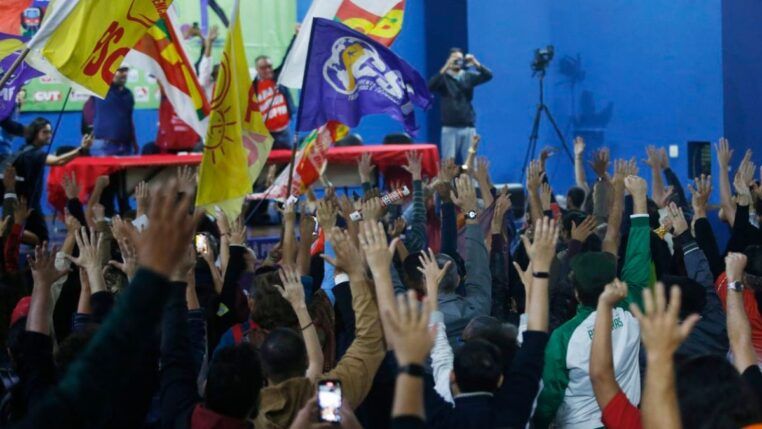 Multidão de sindicalizados em greve levantando as mãos