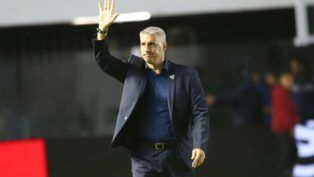 Crespo de terno escuro, acenando para torcida, do campo.