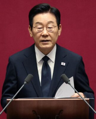 O presidente da Coreia do Sul fala ao microfone à frente de um fundo vermelho